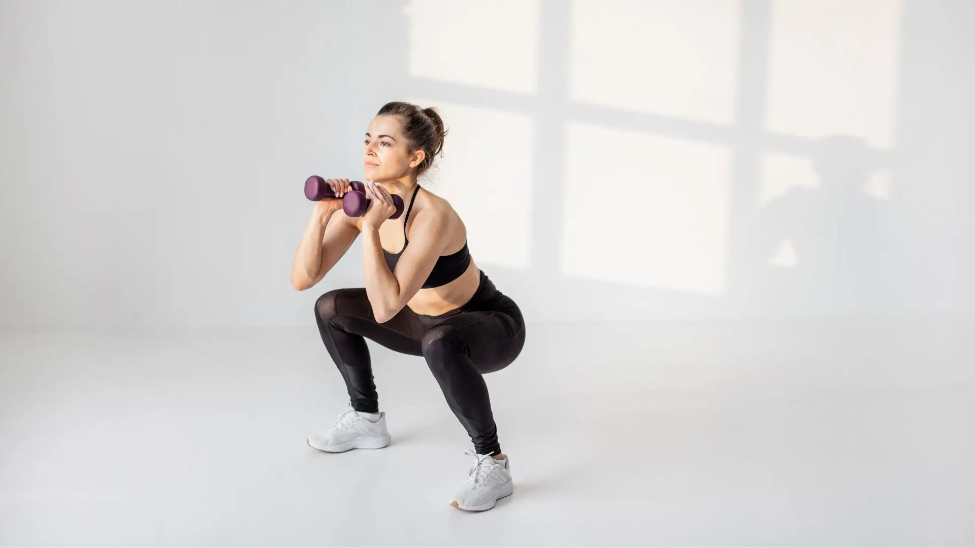 Woman mid-workout pausing for a drink from her bottle.